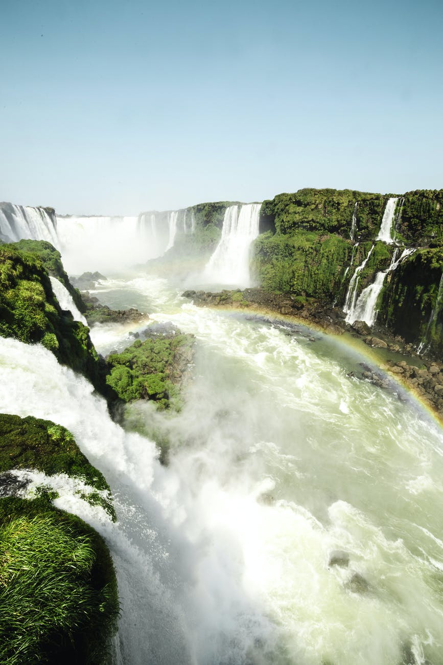 raging water falls falling over grassy cliffs churning water below